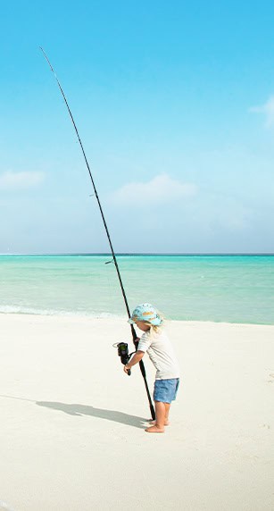 little kid holding a tall fishing rode next to the shore